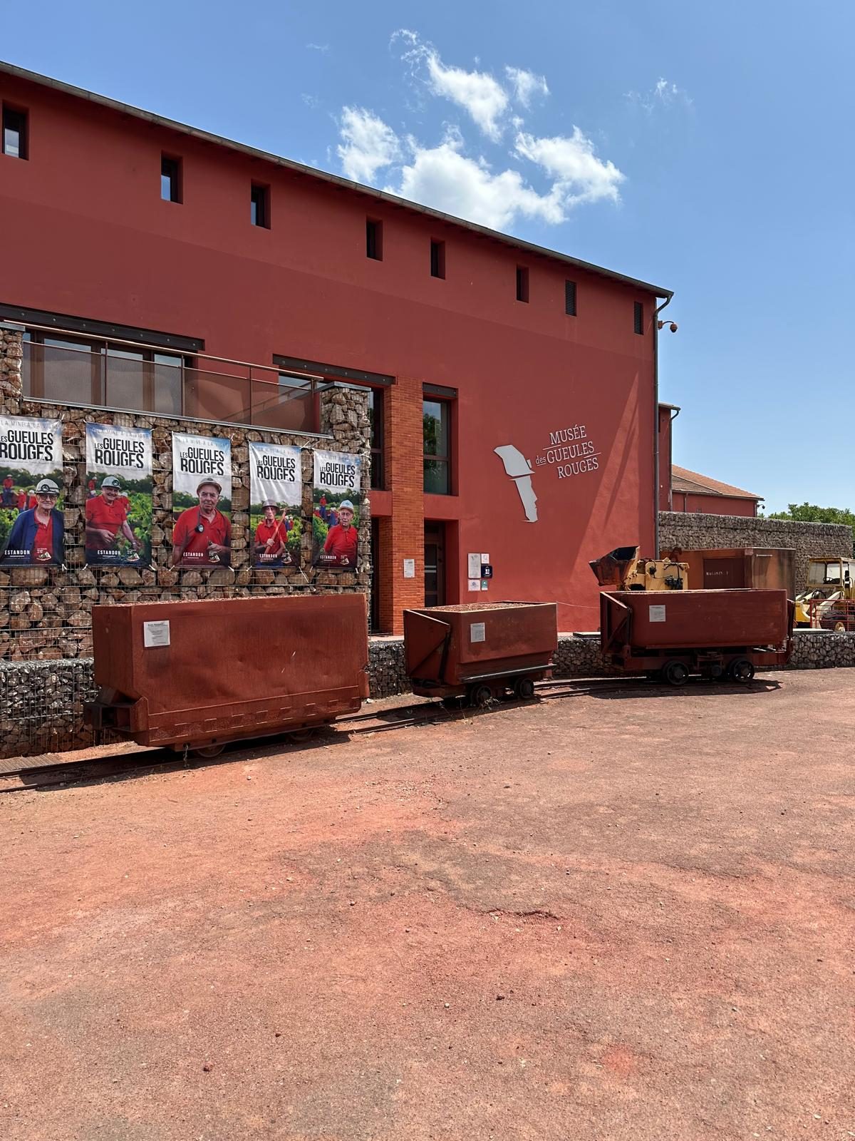 The museum at Tourves: a red building the colour of its subject, with ore wagons standing on rail outside the entrance.